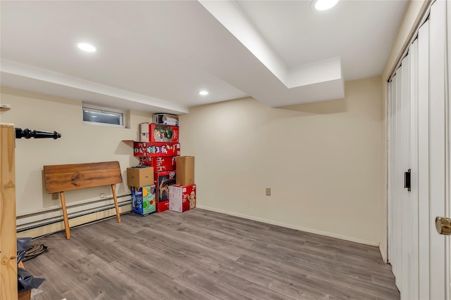 finished below grade area with recessed lighting, a baseboard radiator, baseboards, and wood finished floors