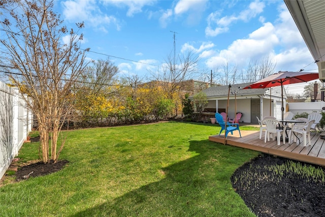 view of yard featuring fence, a wooden deck, and outdoor dining space