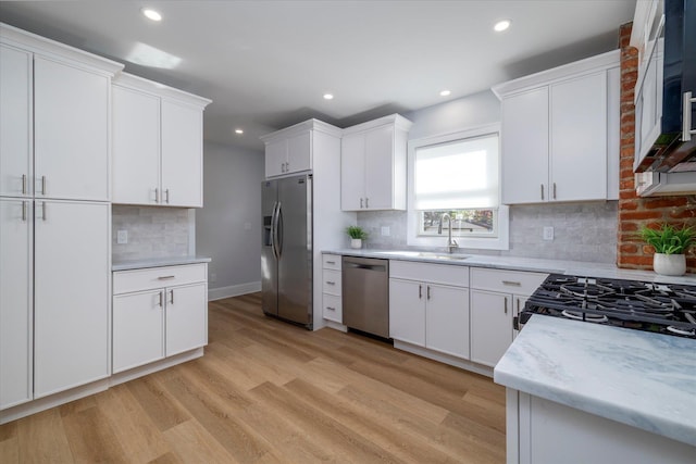 kitchen featuring recessed lighting, a sink, light wood-style flooring, appliances with stainless steel finishes, and backsplash