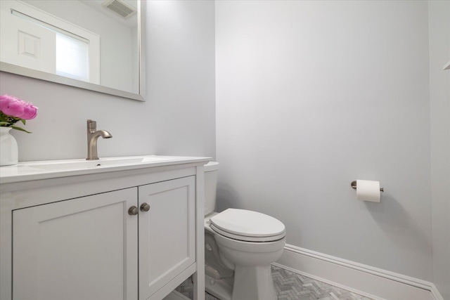 bathroom featuring toilet, baseboards, visible vents, and vanity