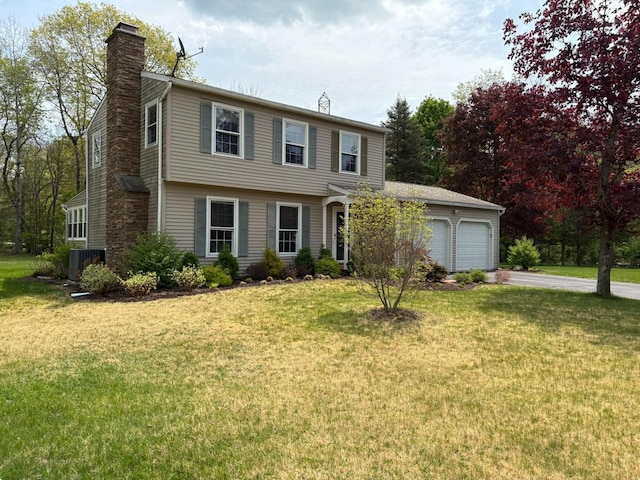 colonial-style house with a front yard, driveway, a chimney, and a garage