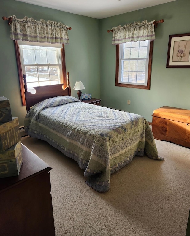 carpeted bedroom featuring multiple windows and a baseboard heating unit