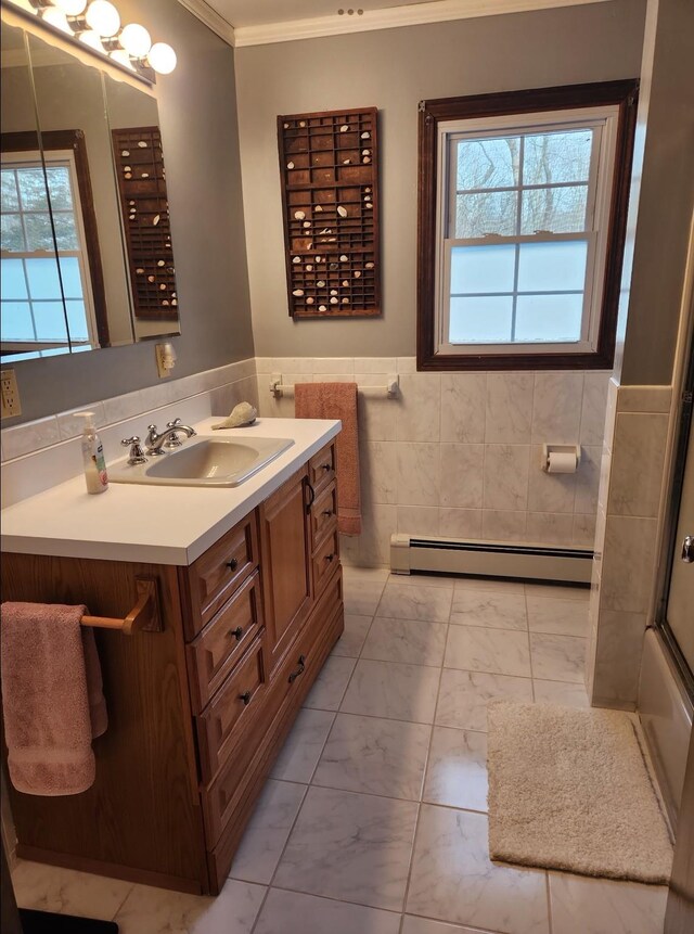 full bathroom featuring tile walls, baseboard heating, marble finish floor, vanity, and ornamental molding
