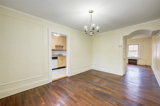 spare room with crown molding, arched walkways, wood finished floors, an inviting chandelier, and radiator