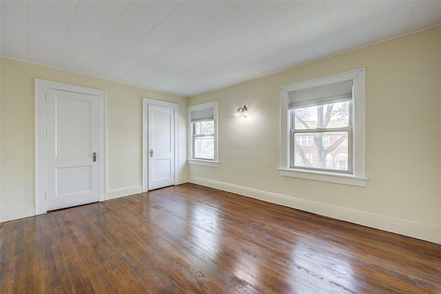 spare room featuring wood-type flooring and baseboards