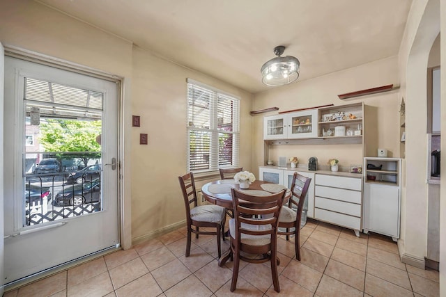 926 Van Nest Ave, Bronx, NY 10462 - dining area featuring baseboards, arched walkways, light tile patterned flooring, and a healthy amount of sunlight
