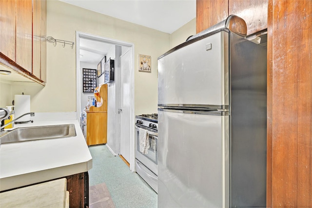 kitchen with a sink, stainless steel appliances, tile patterned floors, and light countertops