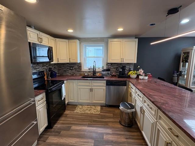 kitchen featuring a sink, backsplash, appliances with stainless steel finishes, dark wood-style floors, and recessed lighting