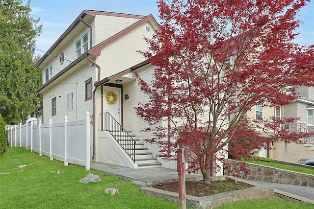 view of front facade with fence, stucco siding, and a front lawn