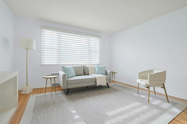 sitting room featuring baseboards, wood finished floors, and a healthy amount of sunlight
