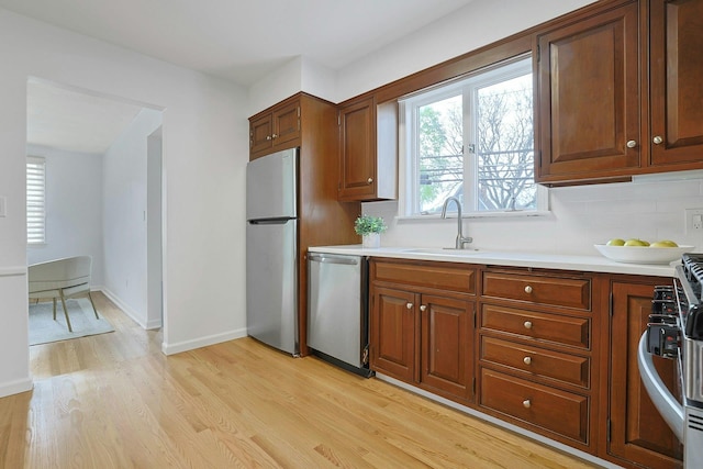 kitchen featuring appliances with stainless steel finishes, light wood-style floors, light countertops, and a sink