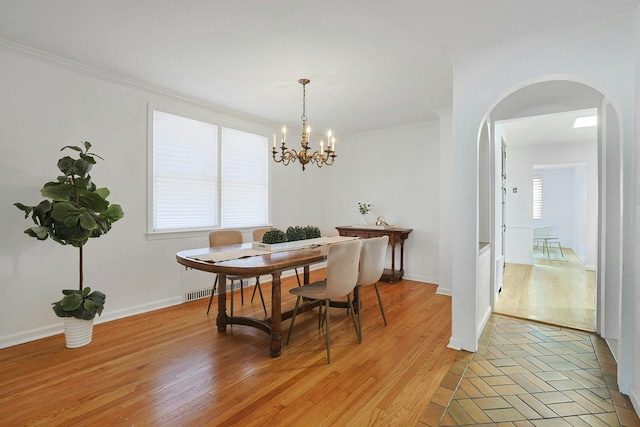 dining room featuring arched walkways, an inviting chandelier, baseboards, light wood-type flooring, and crown molding