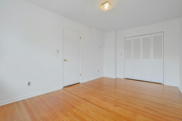 unfurnished bedroom with baseboards, light wood-style floors, and a closet