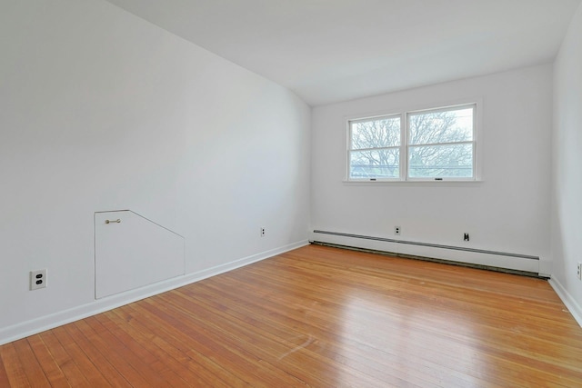spare room with baseboards, light wood-type flooring, and a baseboard heating unit