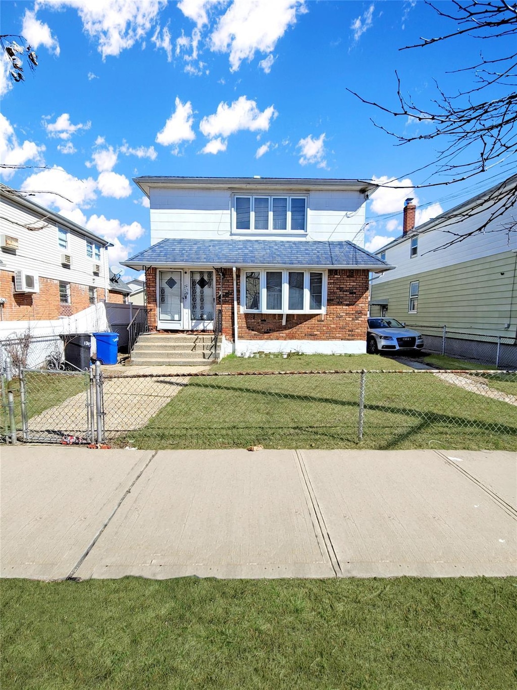 view of front of property featuring a gate, brick siding, fence private yard, and a front yard