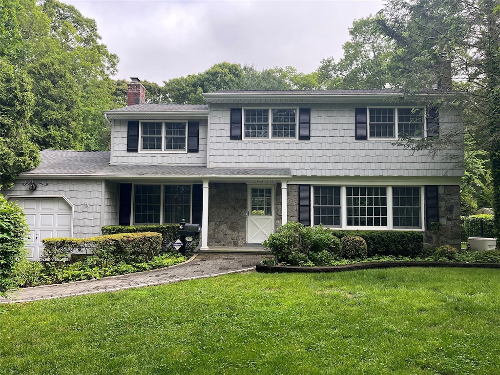 6 Rice Ln, Smithtown, NY 11787 - view of front facade featuring a chimney, an attached garage, a front lawn, and stone siding