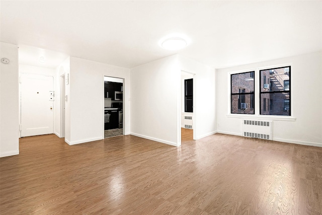 105-15 66th Rd St Unit 4E, Forest Hills, NY 11375 - unfurnished living room featuring baseboards, radiator, and wood finished floors