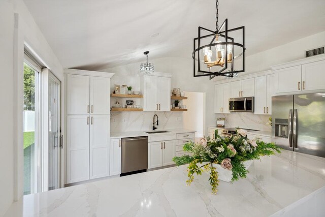 kitchen featuring open shelves, a sink, appliances with stainless steel finishes, a notable chandelier, and backsplash