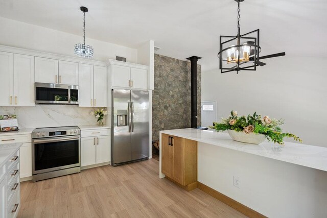 kitchen with light countertops, an inviting chandelier, appliances with stainless steel finishes, and light wood finished floors