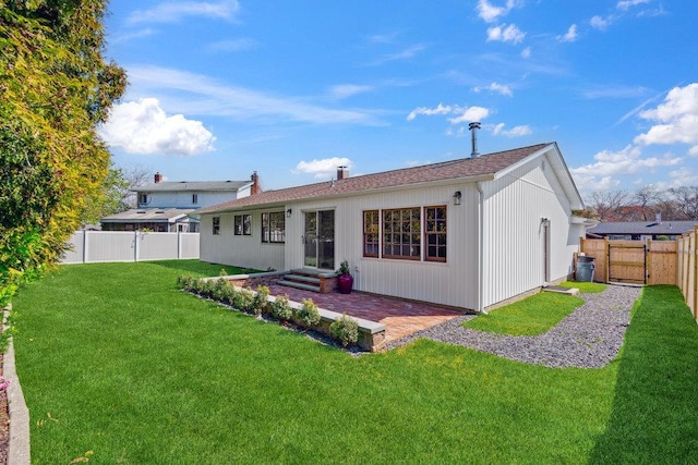 back of property with a lawn, a patio, a shingled roof, and a fenced backyard