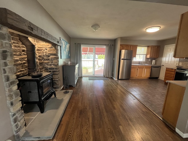 kitchen featuring light countertops, a wood stove, a wealth of natural light, and stainless steel appliances