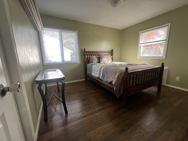 bedroom with dark wood finished floors, baseboards, and multiple windows