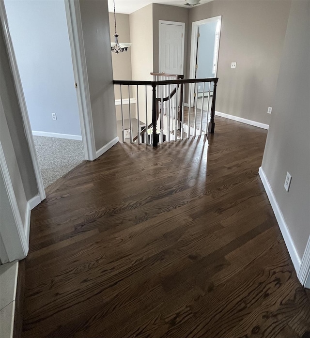 empty room featuring dark wood finished floors, baseboards, and a chandelier
