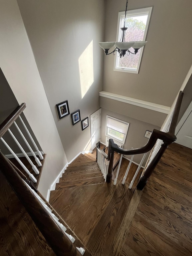 staircase featuring baseboards, wood finished floors, and a high ceiling