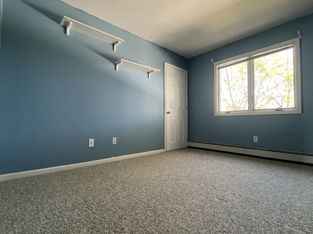 carpeted spare room with a baseboard heating unit and baseboards