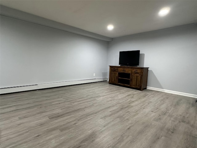 unfurnished living room with a baseboard heating unit, light wood-type flooring, baseboards, and recessed lighting