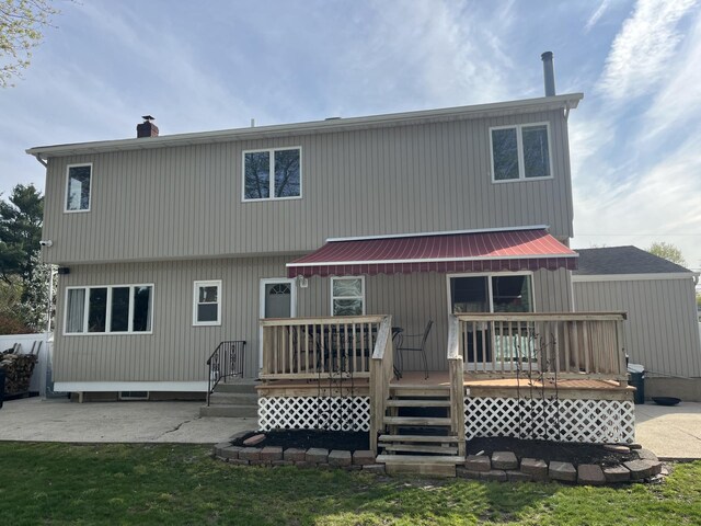 rear view of property with a chimney, a wooden deck, and a patio area