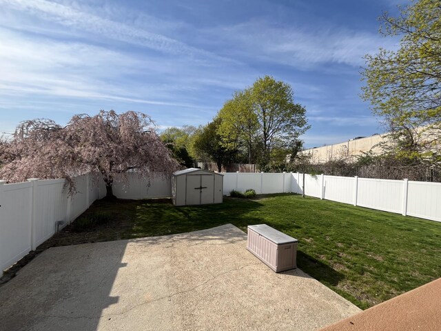 view of yard featuring a patio area, a fenced backyard, an outbuilding, and a storage shed