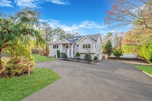raised ranch with a front lawn, fence, and driveway