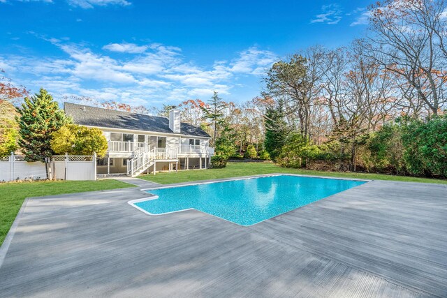 pool featuring stairway, fence, a wooden deck, a lawn, and a sunroom