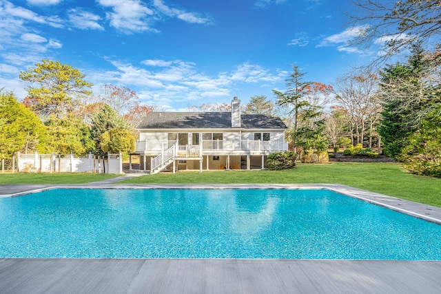 outdoor pool with stairway, fence, a yard, and a deck