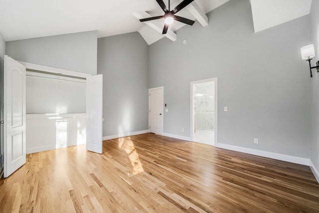 unfurnished living room featuring baseboards, a ceiling fan, wood finished floors, and high vaulted ceiling