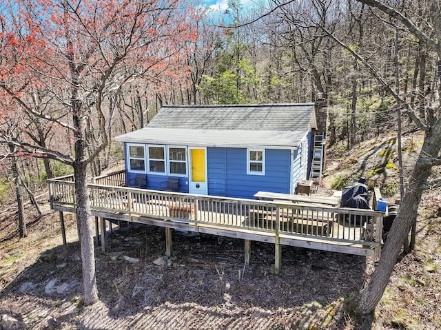 rear view of property featuring a wooden deck and a shingled roof