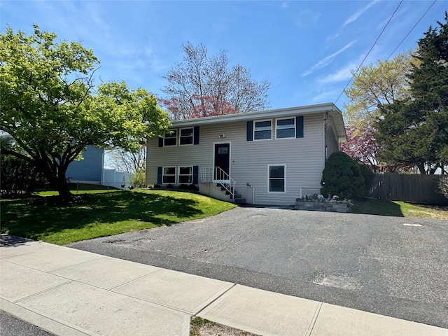 bi-level home featuring driveway, a front yard, and fence
