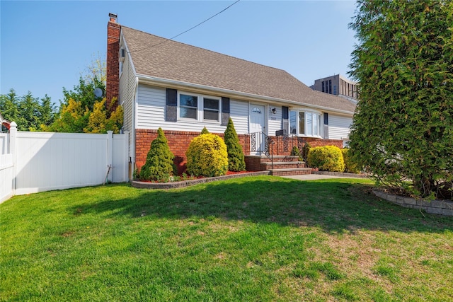 view of front of home featuring a chimney, brick siding, fence, a shingled roof, and a front lawn