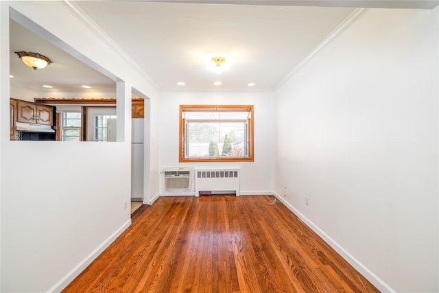 unfurnished room with baseboards, radiator, ornamental molding, and wood finished floors