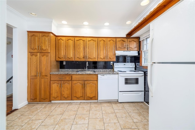 kitchen with brown cabinetry, a sink, under cabinet range hood, and white appliances