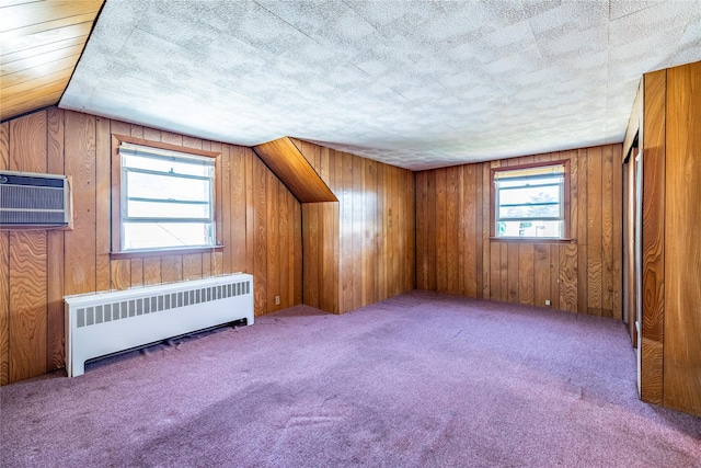 additional living space with radiator heating unit, wooden walls, carpet floors, and a wall mounted AC