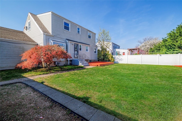 rear view of house featuring fence, roof with shingles, a deck, and a yard