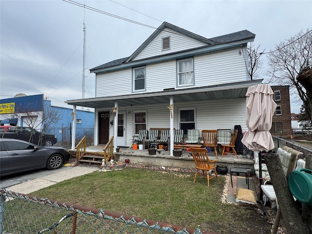 view of front of home with a porch, a front lawn, and fence