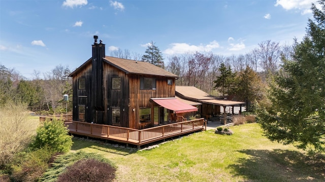 back of house with a lawn, a wooden deck, and a chimney