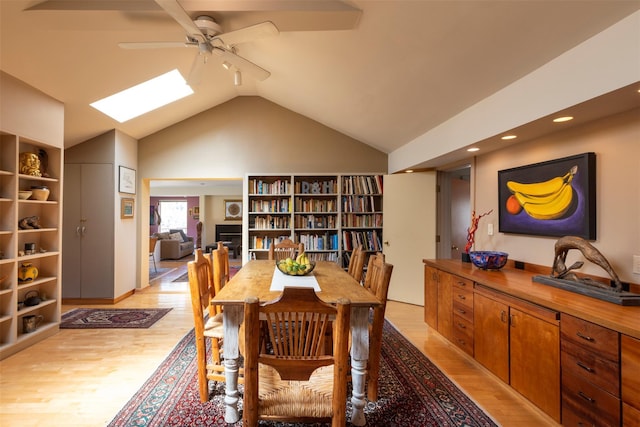 dining space featuring recessed lighting, light wood-style floors, lofted ceiling with skylight, and a ceiling fan