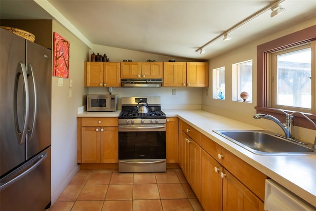 kitchen featuring a sink, stainless steel appliances, light countertops, lofted ceiling, and under cabinet range hood