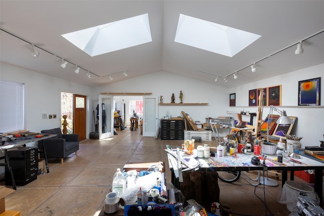 dining area with concrete floors, lofted ceiling with skylight, rail lighting, and a workshop area
