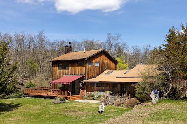 rear view of property featuring a wooden deck, a lawn, and a chimney