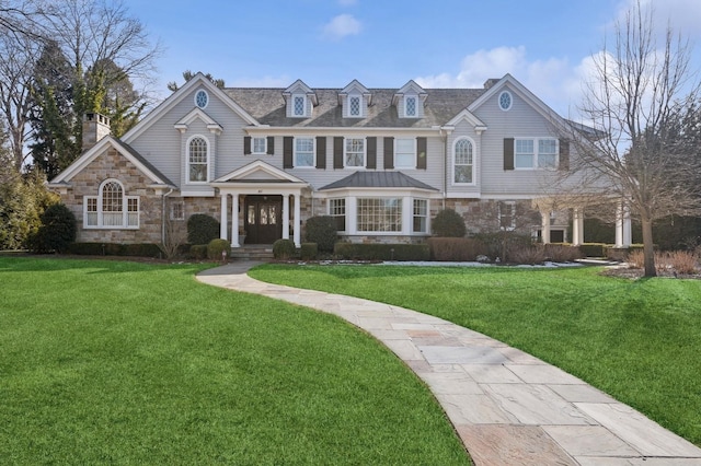 view of front of property with a chimney, a front lawn, and stone siding